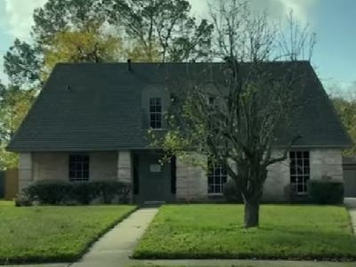It is a two-storeyed grey colored house with a tree in it's garden in front.